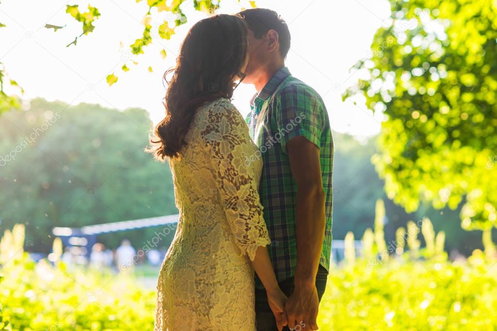 Closeup photo of romantic kissing couple outdoors, side view.