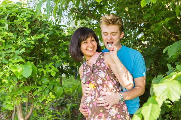 Happy pregnant woman and her husband have fun in the park. Stock Photo