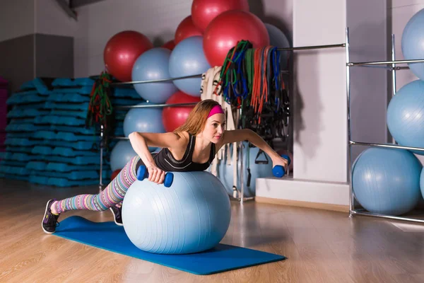 Young sporty woman in gym doing fitness exercice with blue ball — Stock Photo, Image