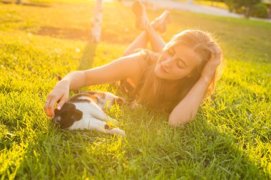 Evcil hayvan ve sahibi kavramı - çim bir kedi ile oynarken güzel kız.