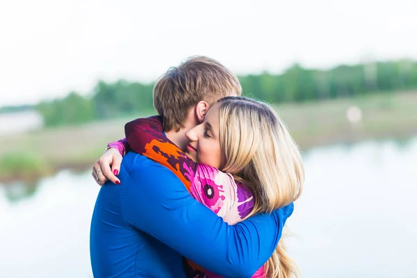 Porträtt av vackra unga par i kärlek omfamna nära sjön. — Stockfoto