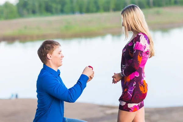 Helgdagar, kärlek, par, relation och dating koncept - romantiska man föreslår att en kvinna på naturen — Stockfoto