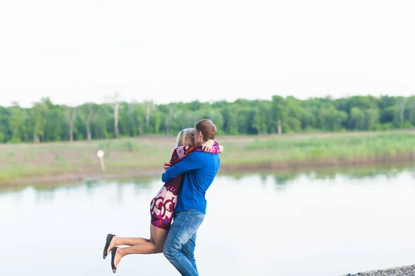 Hermosa joven pareja enamorada abrazando cerca del lago . — Foto de Stock