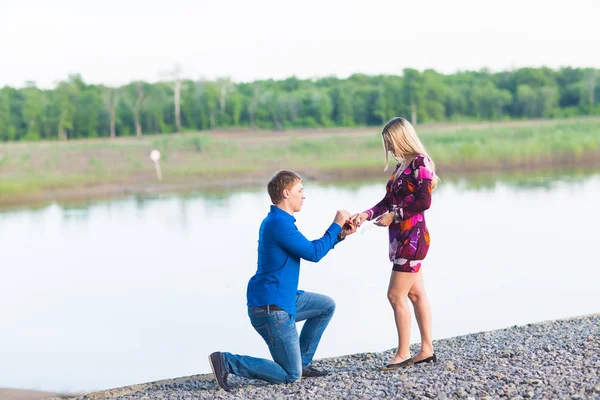 Férias, amor, casal, relacionamento e namoro conceito - homem romântico propondo a uma mulher na natureza — Fotografia de Stock