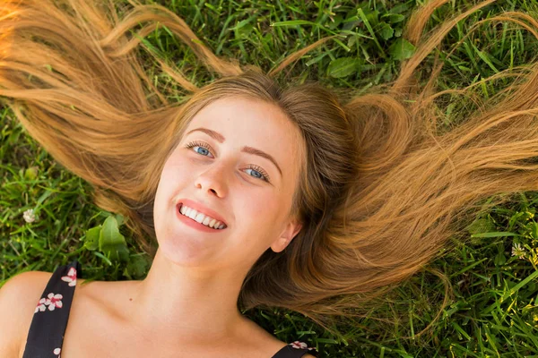 Portrét mladé ženy ležící na trávě — Stock fotografie