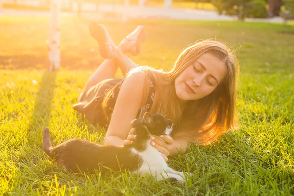 애완 동물 및 소유자 개념-풀밭에서 고양이 함께 재생 하는 아름 다운 소녀. — 스톡 사진