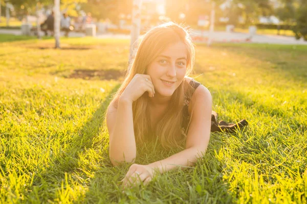 Portret van een jonge vrouw liggend op het gras in de zon — Stockfoto