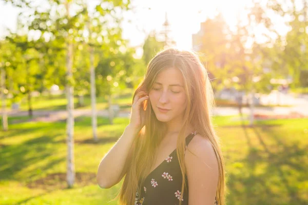 Atraktivní mladá žena těší její čas venku v parku se západem slunce v pozadí — Stock fotografie