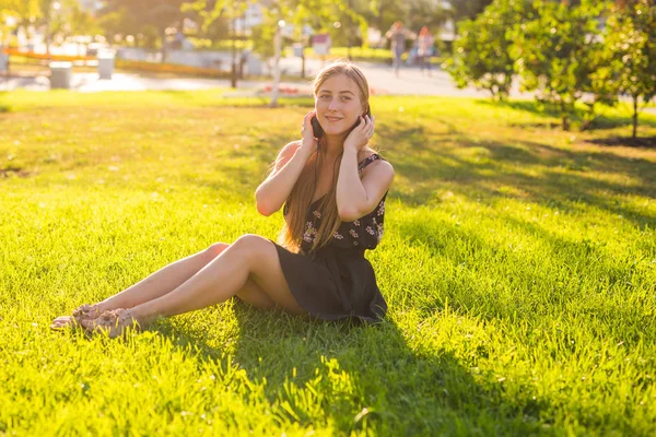 Schöne junge Frau hört Musik im Park — Stockfoto