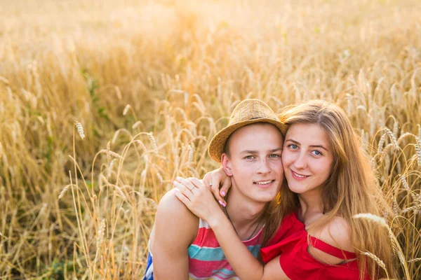 在小麦中享受快乐年轻夫妇现场，夏季。夕阳的光，亮光，复制空间 — 图库照片