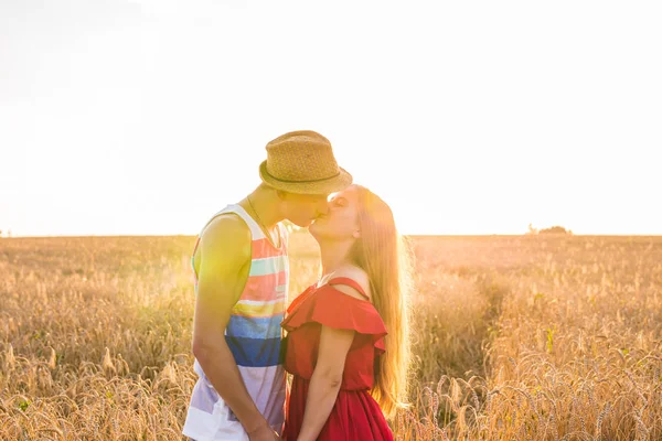 Junges Liebespaar küsst sich auf Feld im Sonnenlicht — Stockfoto