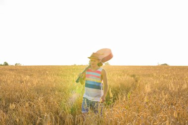 Genç hipster adam bir doğada, yürüme ile bir gitar tutan güneşli bir günde alanında rahatlatıcı.