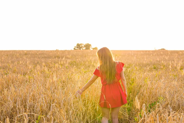 País, naturaleza, vacaciones de verano, vacaciones y el concepto de la gente - mujer joven feliz en vestido rojo en el campo de cereales — Foto de Stock
