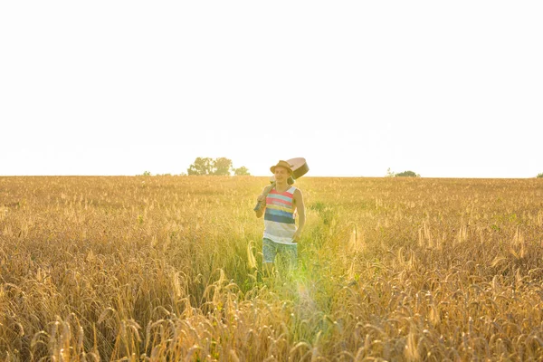 Joven hombre hipster sosteniendo una guitarra con un caminar en la naturaleza, Relajarse en el campo en un día soleado . — Foto de Stock