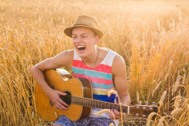 Bir adam çim alandaki gitar çalıyor, gün güneş ışığı ile sakin ol