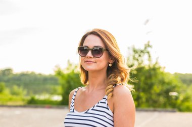 Zamanının dışında arka planda gün batımı ile parkta genç kadının gülüyor.