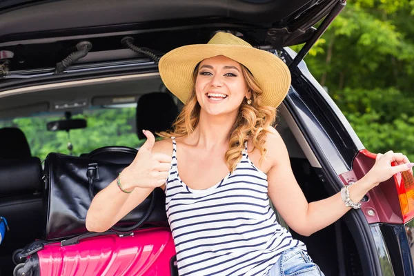 Reise, Tourismus - Frau sitzt im Kofferraum eines Autos mit Koffern, zeigt Daumen hoch, bereit für den Urlaub. — Stockfoto