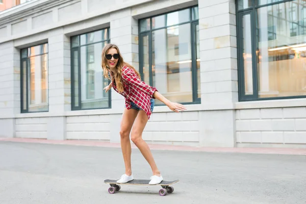 Молодая женщина едет на скейтборде. Женский конькобежный спорт в городе . — стоковое фото