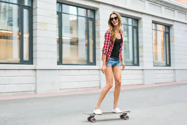 Летние каникулы, экстремальный спорт и люди концепция - счастливая девушка катание на скейтборде по улице города — стоковое фото