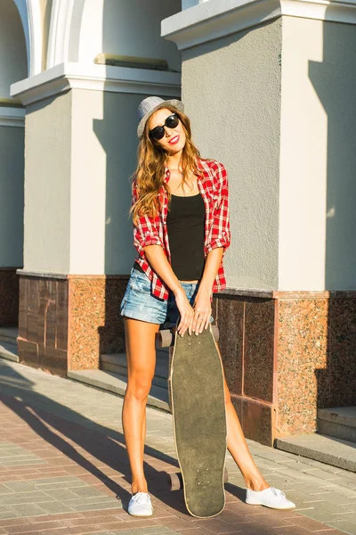 Mooie jonge vrouw in zonnebril met skate, straat mode levensstijl. — Stockfoto