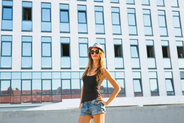 Zonnige levensstijl mode portret van de jonge stijlvolle hipster vrouw lopen op de straat, het dragen van trendy outfit en hoed. — Stockfoto