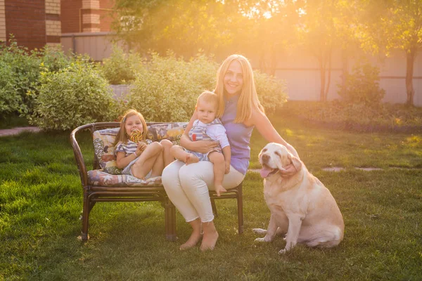 Madre y su hija e hijo en el jardín con un perro perdiguero de oro — Foto de Stock