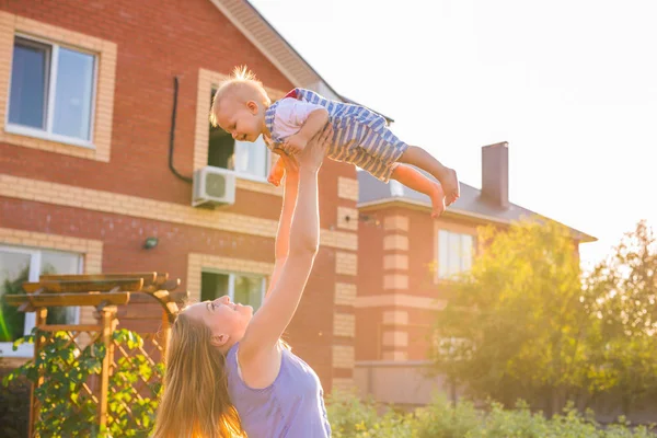 Joyeux famille harmonieuse à l'extérieur. mère vomit bébé, riant et jouant en été sur la nature. — Photo