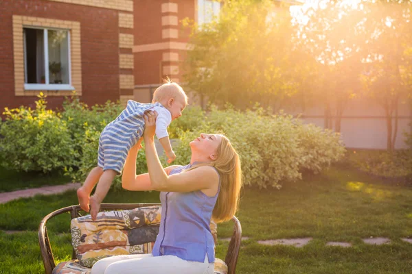 Glad harmonisk familj utomhus. mamma kräks bebis upp, skrattar och leker på sommaren på naturen. — Stockfoto