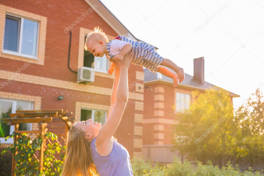 happy harmonious family outdoors. mother throws baby up, laughing and playing in the summer on the nature.