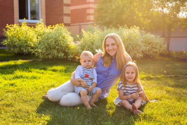 Lycklig mamma och två barn i trädgården. — Stockfoto