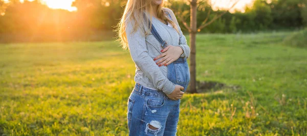 Pregnant woman hugging her belly outdoors — Stock Photo, Image