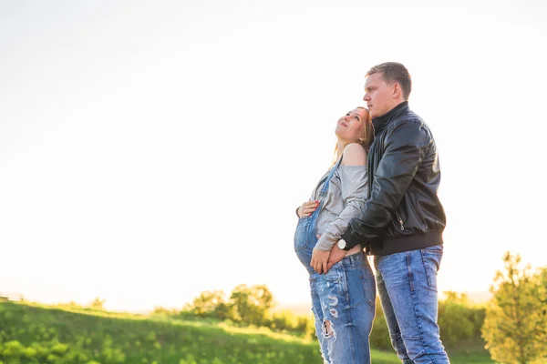 Счастливая молодая беременная пара, обнимающая природу — стоковое фото