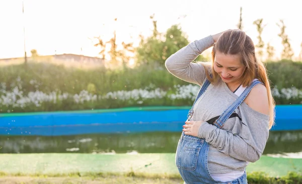 Mujer embarazada abrazando su vientre al aire libre — Foto de Stock