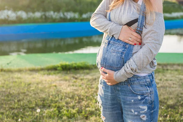 Primo piano della donna incinta che abbraccia il suo stomaco all'aperto — Foto Stock