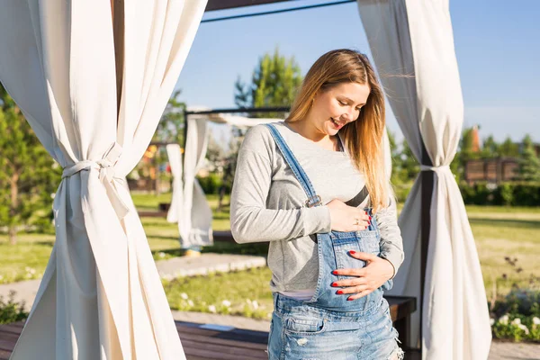 Gravid kvinna kramar hennes mage utomhus — Stockfoto