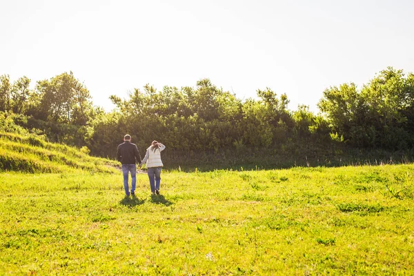 Hombre y mujer tomados de la mano y caminando sobre la naturaleza, vista trasera — Foto de Stock