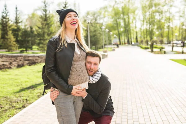 Stylový těhotenství koncept - portrét několika bokovky manžela a manželky v trendy oblečení, procházky v městském parku — Stock fotografie