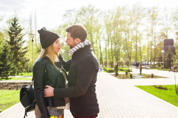 Eleganta graviditet koncept - porträtt av par hipsters man och hustru i trendiga kläder gå i stadsparken — Stockfoto