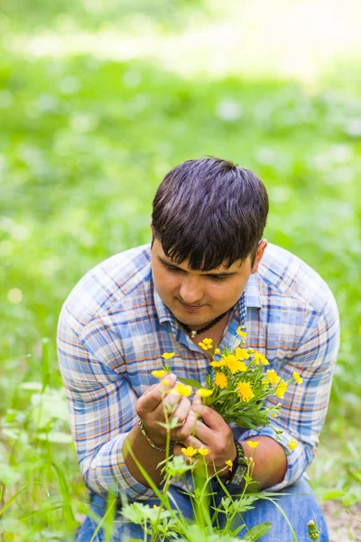 Joven hombre recogiendo flores para su mujer — Foto de Stock