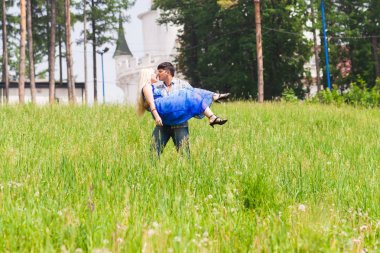 Onun kız arkadaşı çim sahada onun kollarında taşıyan bir genç adam. Çift eğleniyor doğada bir yaz gününde.