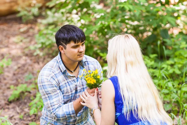 Jovem dando um dente de leão flor para namorada ao ar livre — Fotografia de Stock