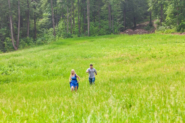 Happy couple running on a meadow in summer nature — Stock Photo, Image