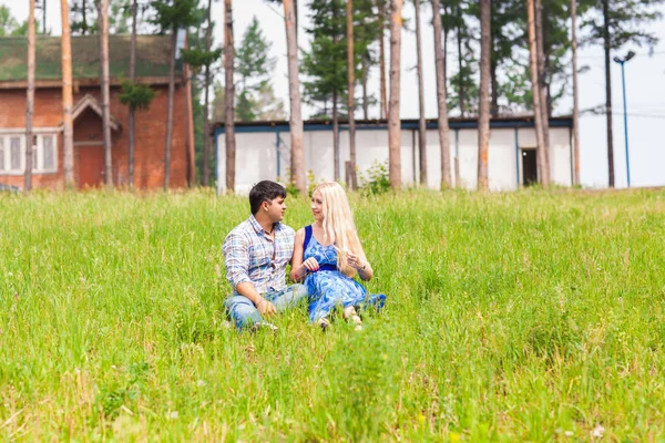 Jovem casal sentado na grama e relaxante — Fotografia de Stock