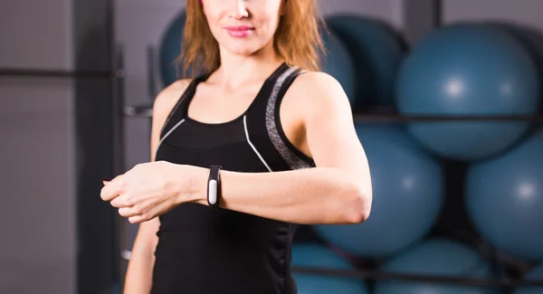 Sport, fitness, technology and people concept - young woman with activity tracker and smartphone in gym close-up — Stock Photo, Image