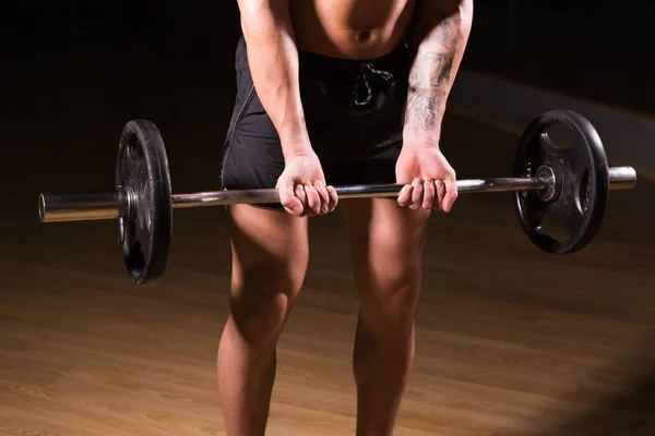 Gespierde man trainen in de sportschool doen oefeningen met barbell close-up, sterke mannelijke naakte torso abs. — Stockfoto