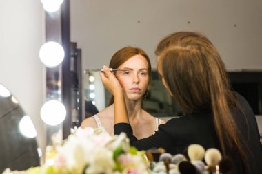 Kızıl saçlı genç kadın profesyonel makyaj yapıyor sanatçı olun