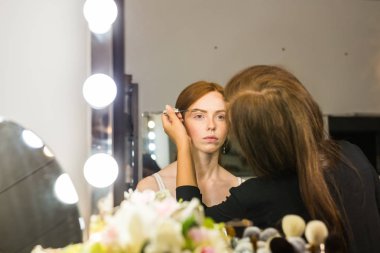 Kızıl saçlı genç kadın profesyonel makyaj yapıyor sanatçı olun