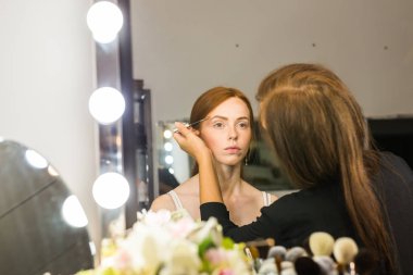 Kızıl saçlı genç kadın profesyonel makyaj yapıyor sanatçı olun