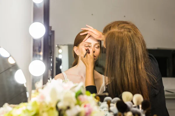 Maquillar artista haciendo profesional maquillaje de mujer joven — Foto de Stock