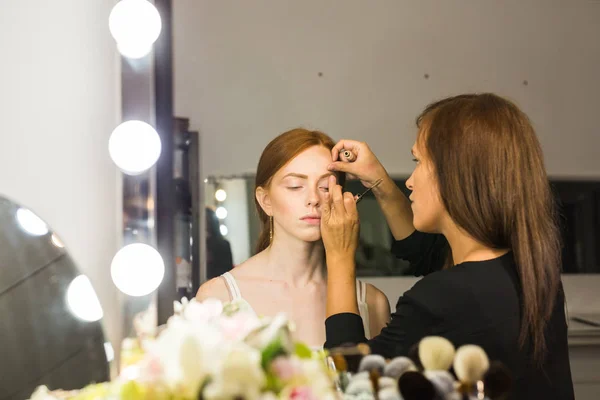 Maquillar artista haciendo profesional maquillaje de mujer joven — Foto de Stock